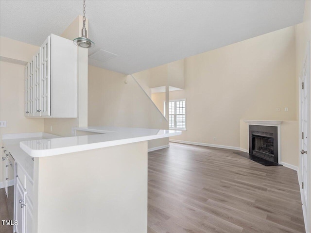 kitchen featuring light countertops, light wood-style flooring, glass insert cabinets, white cabinetry, and baseboards