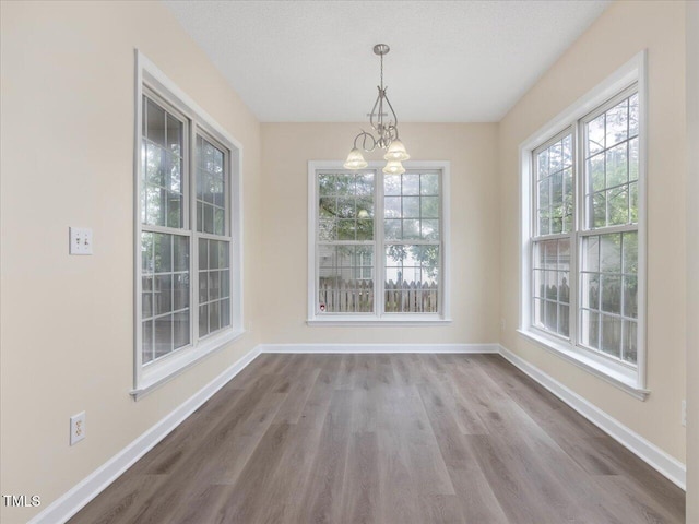 unfurnished dining area with baseboards, dark wood-style flooring, and a chandelier