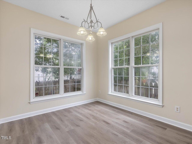unfurnished dining area with a chandelier, wood finished floors, and baseboards