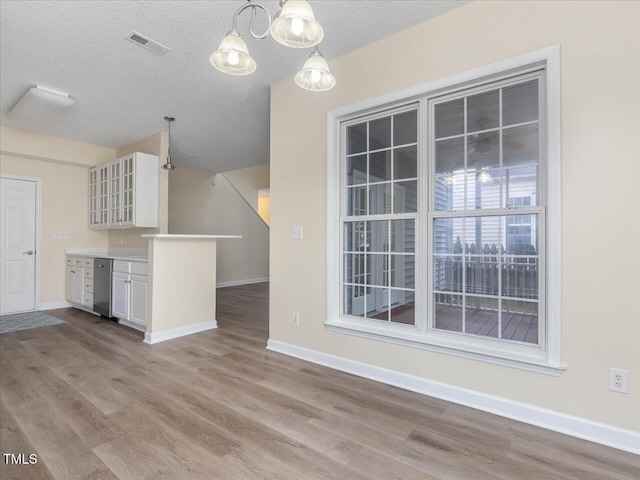 kitchen with white cabinetry, wood finished floors, glass insert cabinets, and a textured ceiling