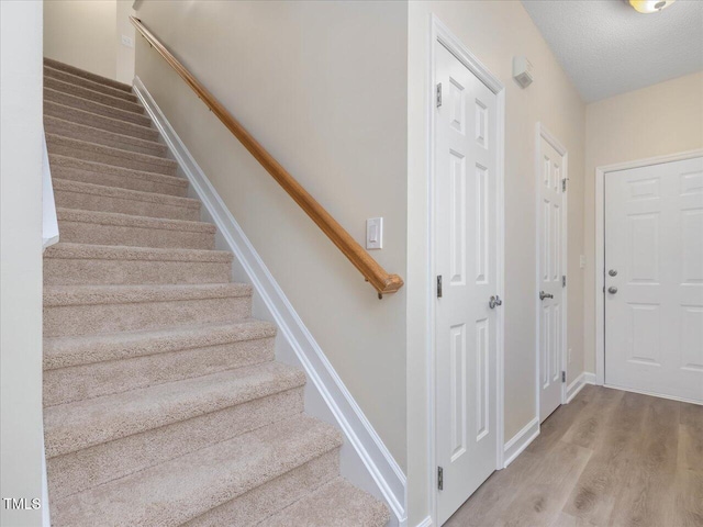 stairs with wood finished floors and baseboards