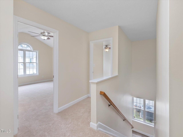 corridor featuring an upstairs landing, carpet flooring, vaulted ceiling, and baseboards