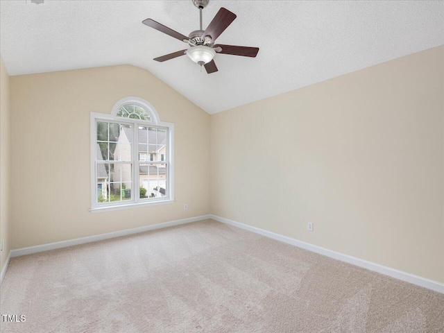 unfurnished room with carpet flooring, ceiling fan, vaulted ceiling, baseboards, and a textured ceiling