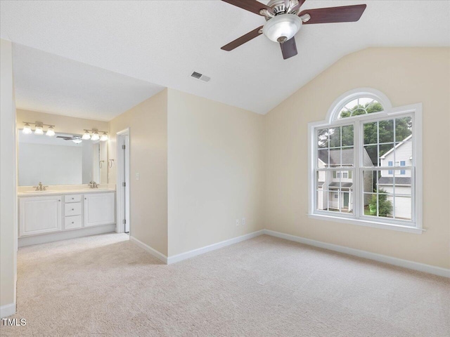 unfurnished bedroom with light carpet, a sink, ensuite bathroom, vaulted ceiling, and baseboards