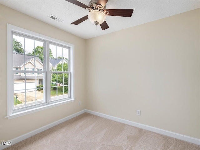 unfurnished room with baseboards, light colored carpet, a ceiling fan, and a textured ceiling