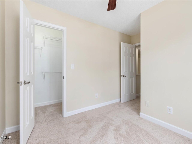 unfurnished bedroom featuring carpet floors, a walk in closet, a closet, and baseboards