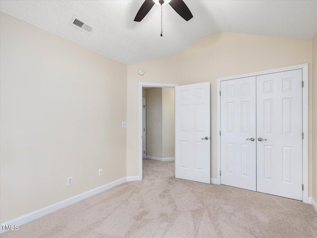 unfurnished bedroom with vaulted ceiling, carpet floors, baseboards, a closet, and ceiling fan