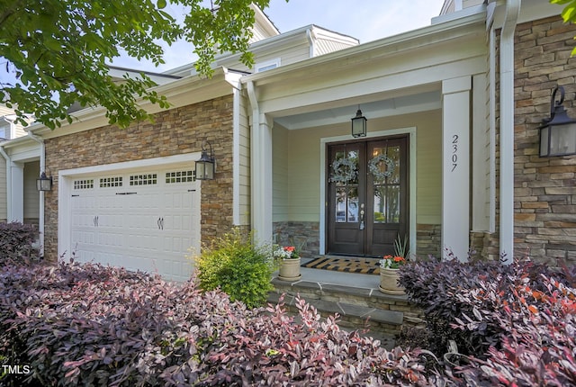 property entrance with a porch, a garage, french doors, and stone siding
