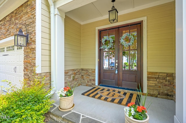 property entrance featuring french doors, covered porch, and stone siding