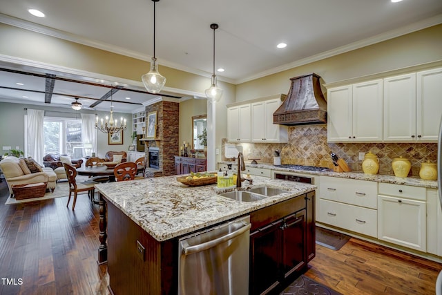 kitchen with a sink, stainless steel appliances, custom range hood, tasteful backsplash, and ornamental molding
