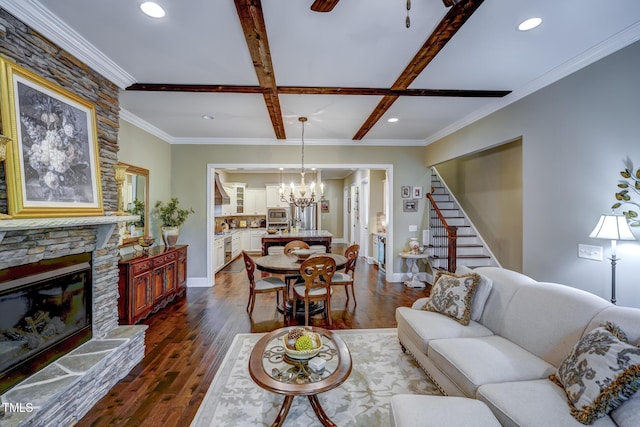 living area featuring a chandelier, a stone fireplace, dark wood finished floors, stairs, and baseboards