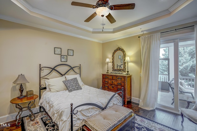 bedroom featuring ornamental molding, access to exterior, wood finished floors, and a raised ceiling