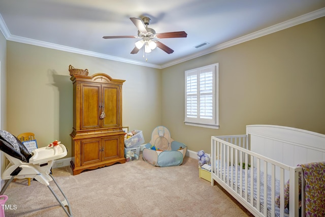 carpeted bedroom featuring visible vents, ornamental molding, a crib, and ceiling fan