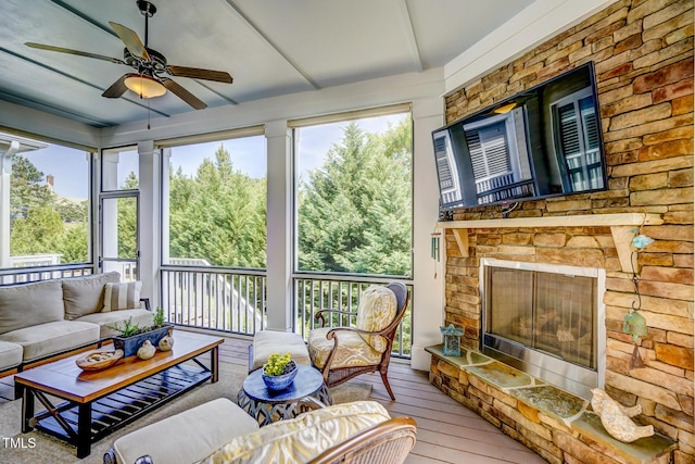 sunroom featuring a ceiling fan and an outdoor living space with a fireplace