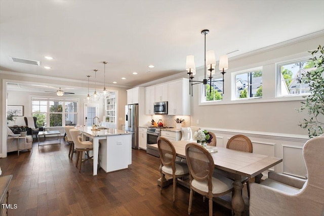 dining area featuring visible vents, wainscoting, crown molding, and dark wood-style floors