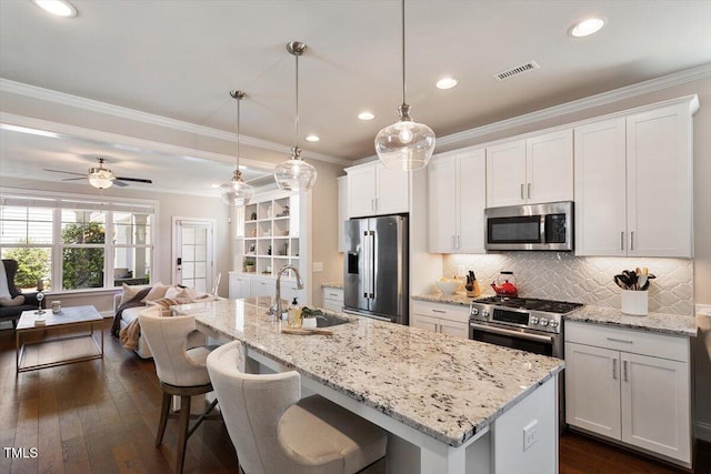 kitchen featuring crown molding, a sink, stainless steel appliances, open floor plan, and visible vents