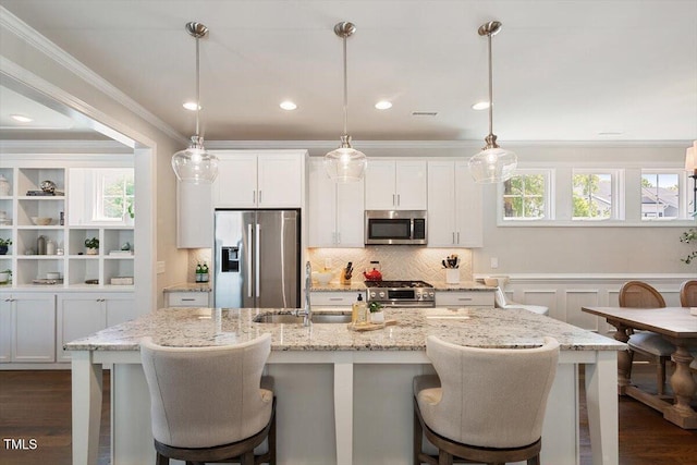 kitchen with a kitchen breakfast bar, white cabinets, a sink, dark wood finished floors, and appliances with stainless steel finishes