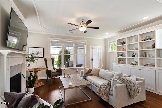 living room with a fireplace, ceiling fan, ornamental molding, and dark wood-type flooring