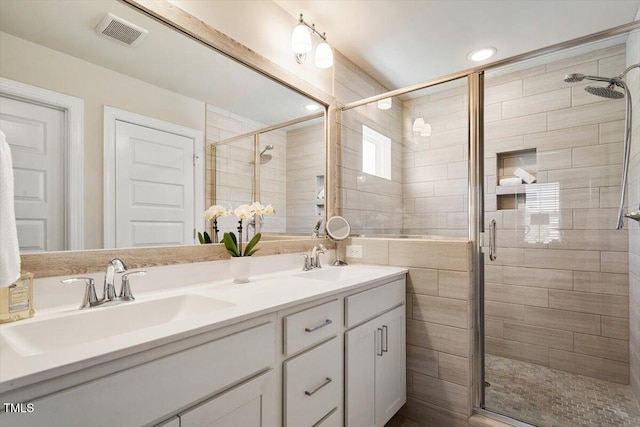 bathroom with a sink, a stall shower, and visible vents