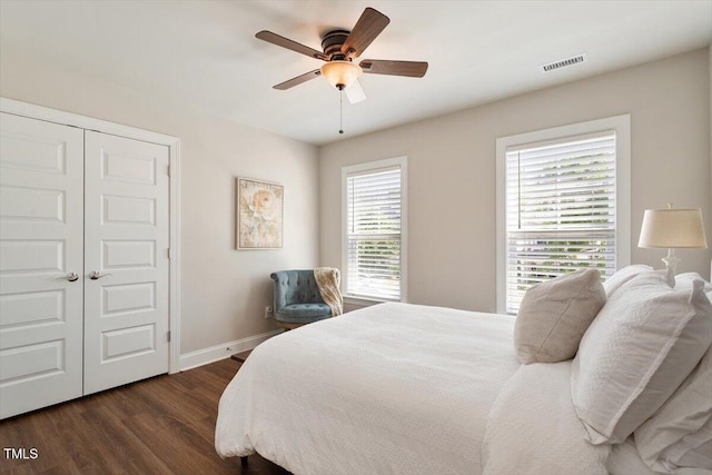 bedroom featuring dark wood-style flooring, ceiling fan, baseboards, visible vents, and a closet