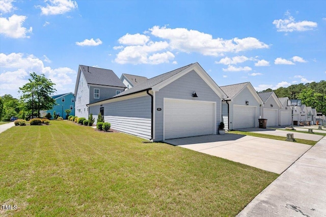 view of side of property with a garage, a residential view, a yard, and driveway