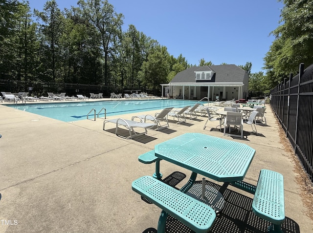 community pool with a patio area and fence