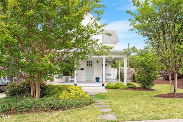 view of front of home with a front yard, ceiling fan, and covered porch