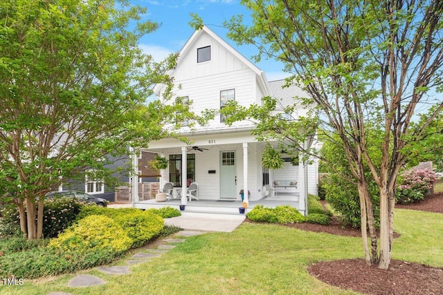 view of front facade featuring a front lawn, a porch, board and batten siding, and a ceiling fan