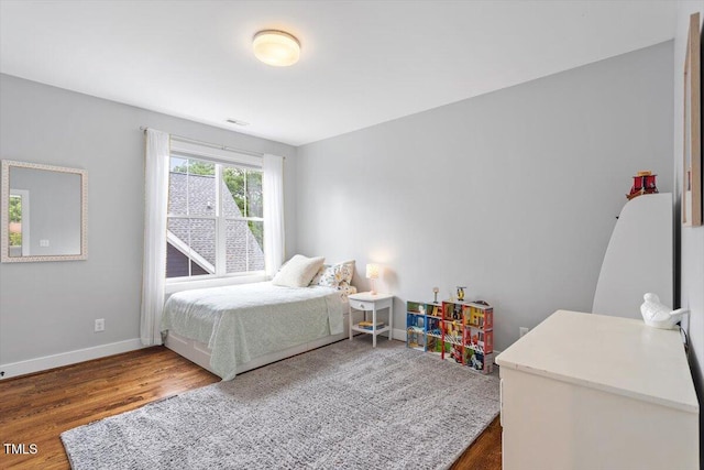 bedroom featuring baseboards, visible vents, and wood finished floors