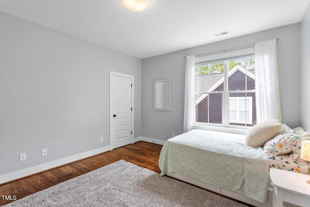 bedroom with visible vents, wood finished floors, and baseboards
