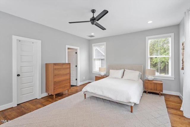 bedroom with wood finished floors, visible vents, baseboards, and multiple windows
