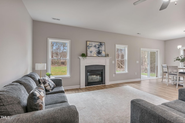 3803 Huntcliff Dr, La Grange, NC 28551 - living area with light wood-style flooring, a ceiling fan, a glass covered fireplace, and baseboards