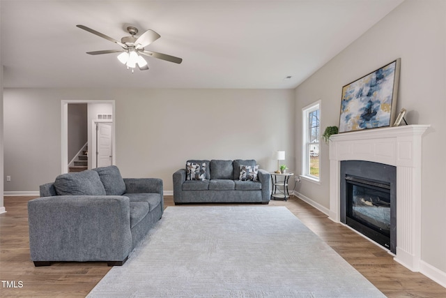 3803 Huntcliff Dr, La Grange, NC 28551 - living area with baseboards, a ceiling fan, wood finished floors, a glass covered fireplace, and stairway