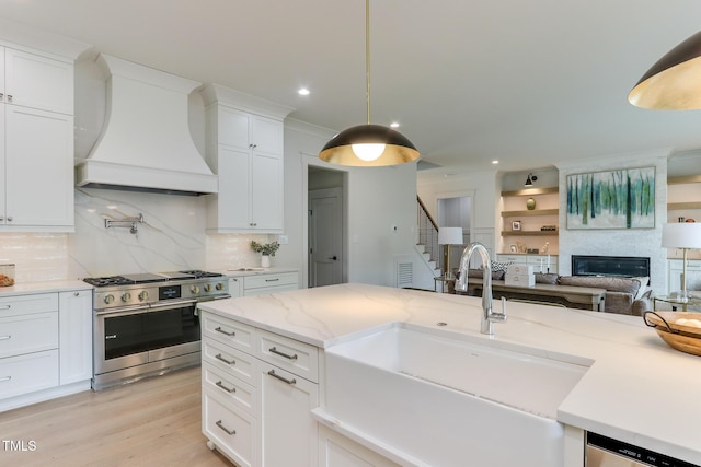 kitchen with a sink, custom exhaust hood, stainless steel appliances, and white cabinets