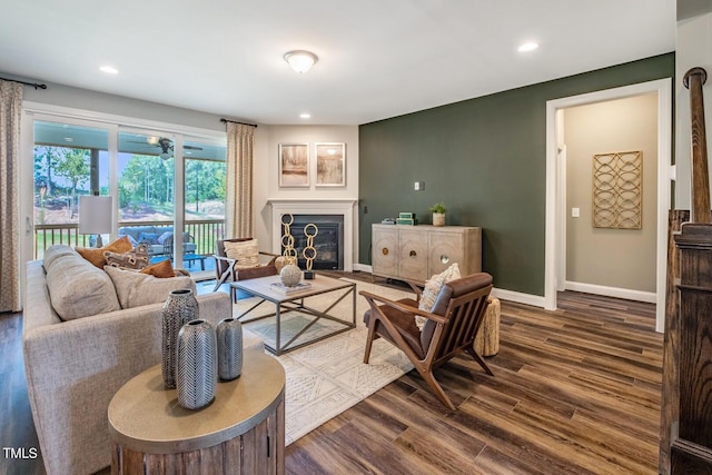 living room featuring dark wood-style flooring, a glass covered fireplace, recessed lighting, and baseboards