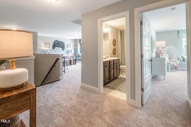 hallway featuring an upstairs landing, visible vents, baseboards, and light carpet