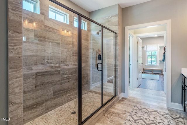 bathroom featuring a wealth of natural light, wood finished floors, vanity, and a stall shower