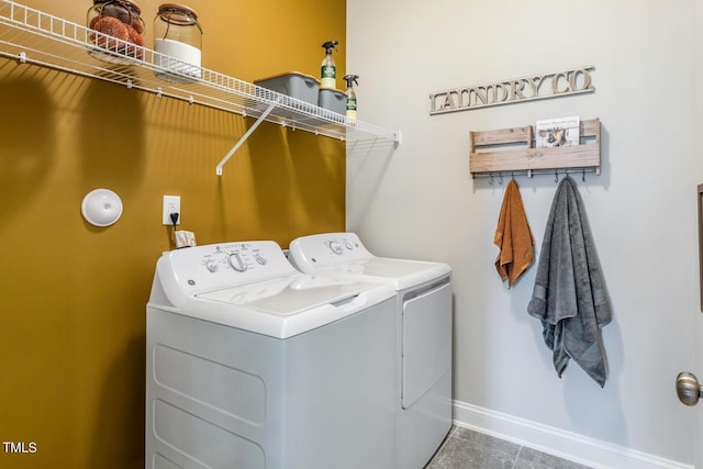 clothes washing area featuring washing machine and dryer, tile patterned flooring, laundry area, and baseboards