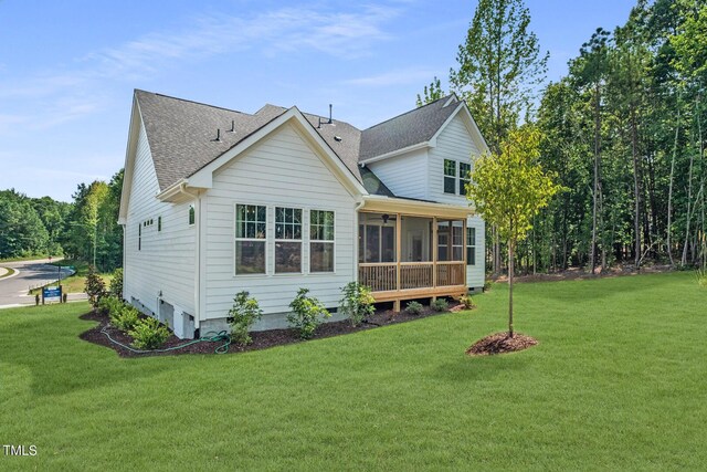 rear view of property featuring a lawn, a sunroom, and roof with shingles
