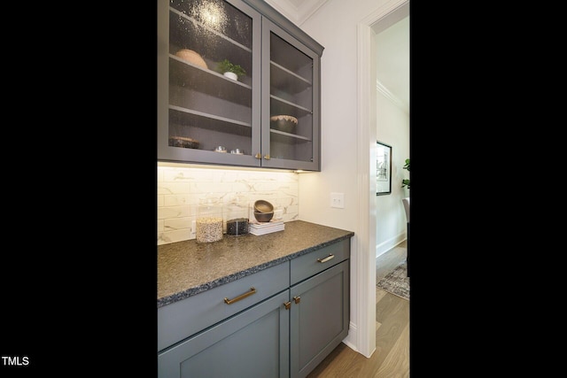 bar featuring ornamental molding, backsplash, and light wood-style floors