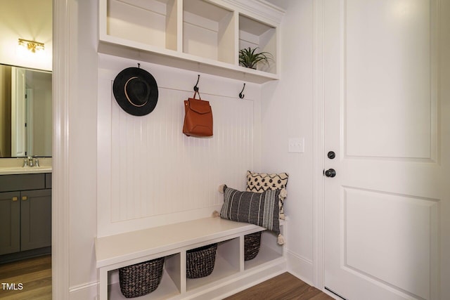 mudroom with dark wood-style flooring, baseboards, and a sink