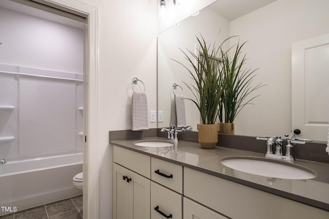bathroom with toilet, double vanity, and a sink