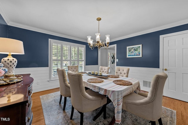 2409 Beechview Ct, Raleigh, NC 27615 - dining space featuring wainscoting, a chandelier, ornamental molding, and light wood-type flooring