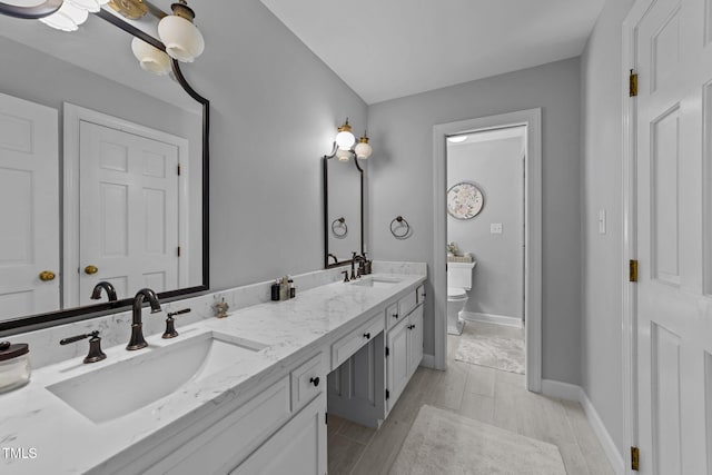 2409 Beechview Ct, Raleigh, NC 27615 - full bath with toilet, wood finished floors, double vanity, and baseboards