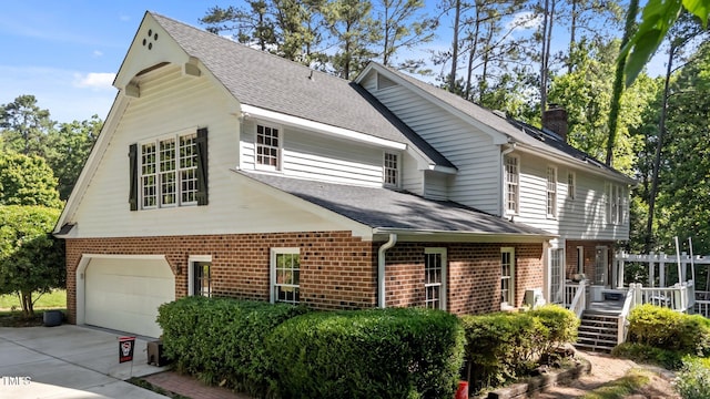 2409 Beechview Ct, Raleigh, NC 27615 - view of front facade featuring an attached garage, a shingled roof, brick siding, driveway, and a wooden deck