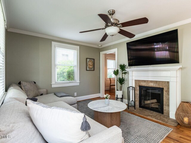 living room with ceiling fan, ornamental molding, wood finished floors, and a tile fireplace