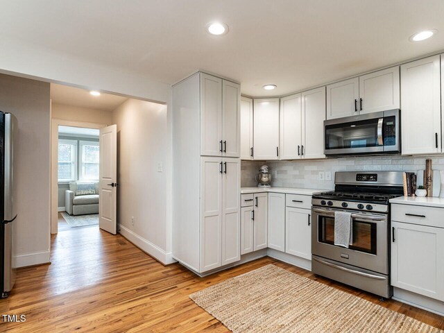 kitchen featuring light countertops, baseboards, tasteful backsplash, and stainless steel appliances