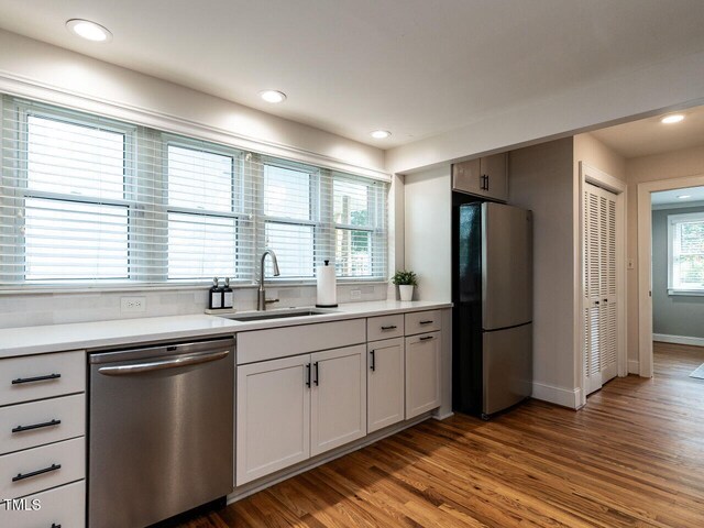 kitchen with light countertops, stainless steel appliances, a sink, and wood finished floors