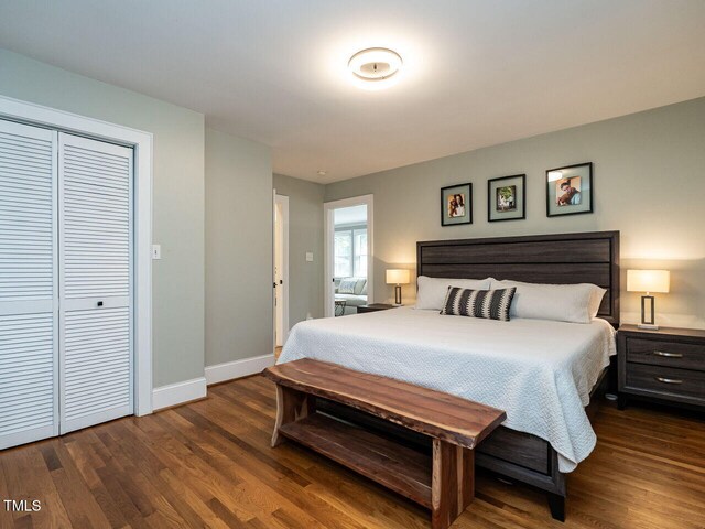 bedroom featuring dark wood-style flooring, baseboards, and a closet