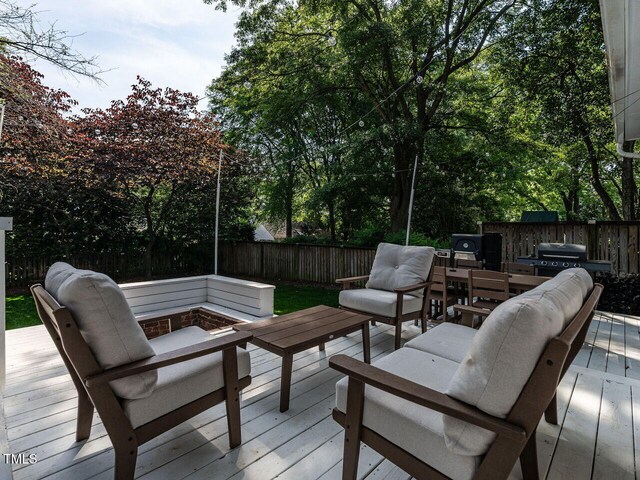 deck with a fenced backyard, an outdoor living space with a fire pit, and grilling area